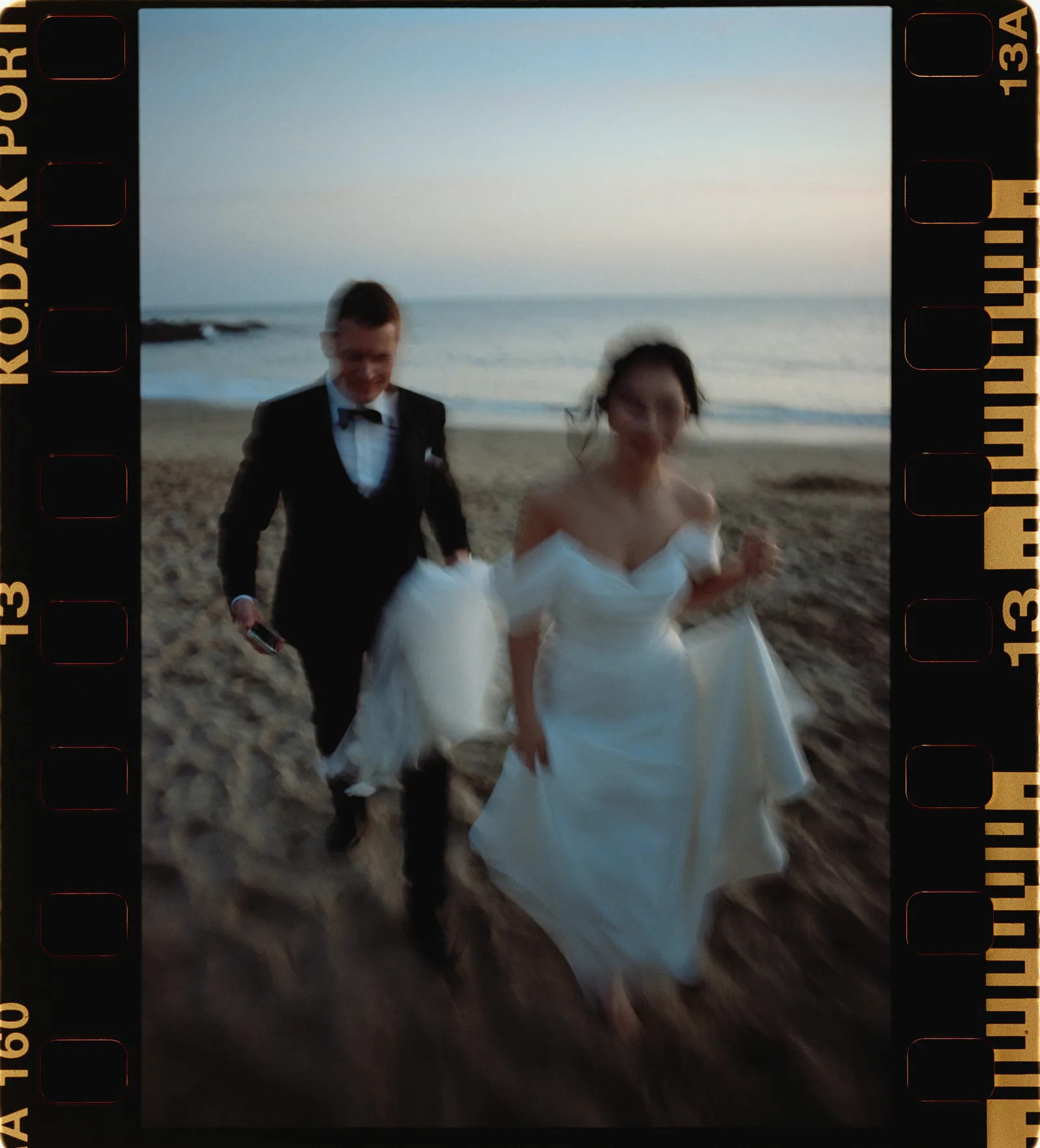 Blurred couple walking on beach — visible Kodak Portra film border