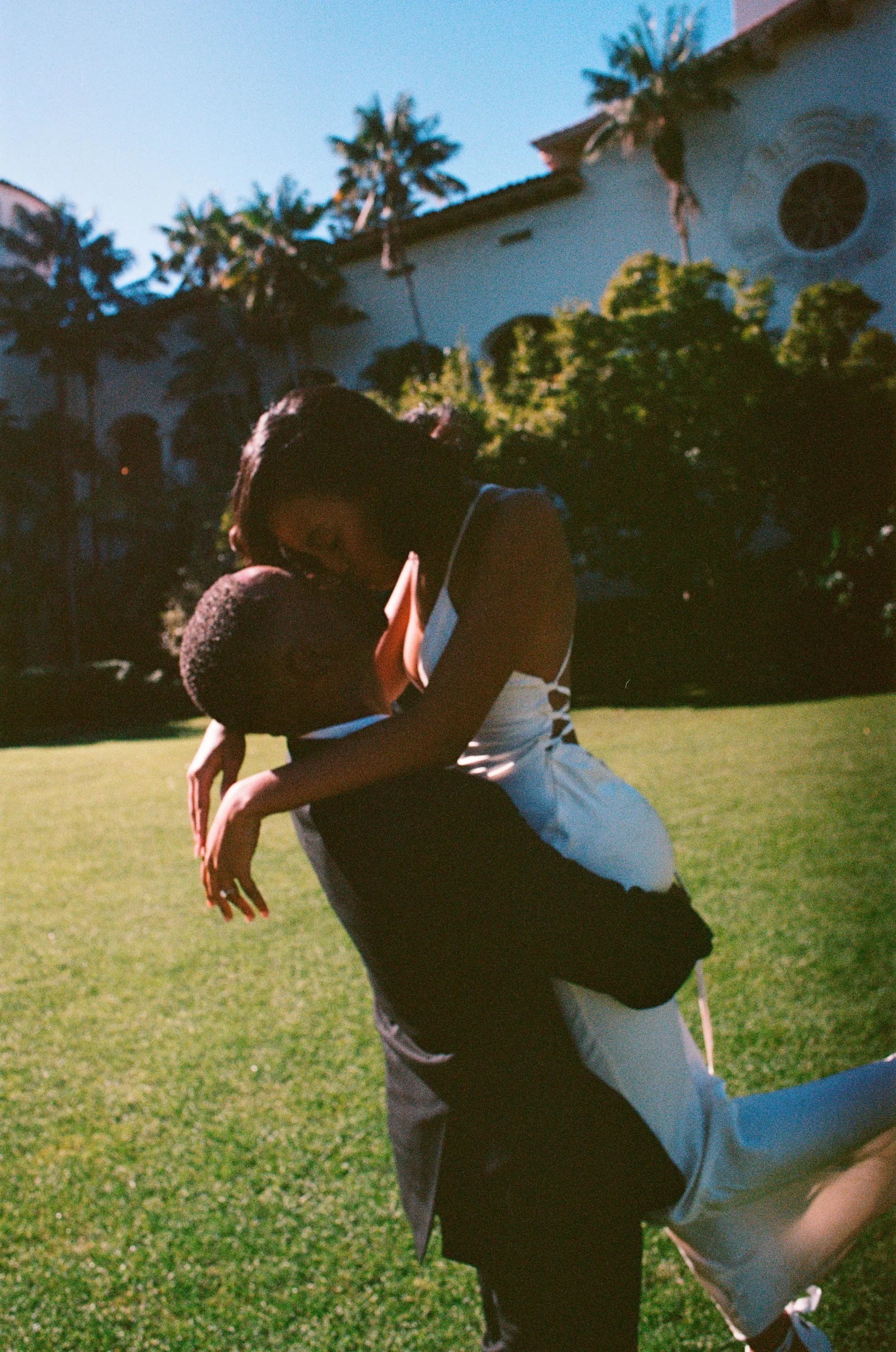 Groom carrying bride mid-kiss outdoors