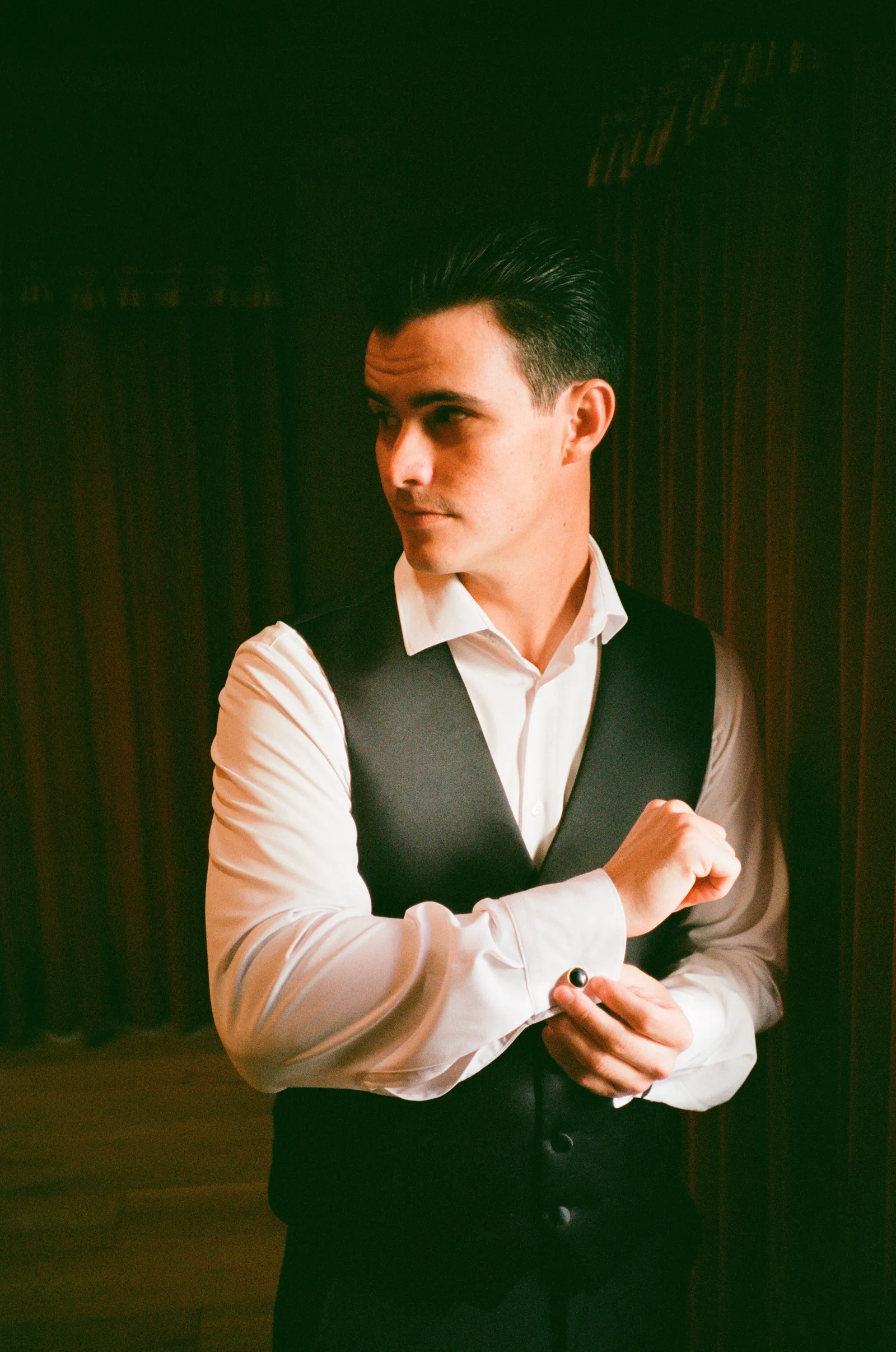 Groom by window — moody warm portrait